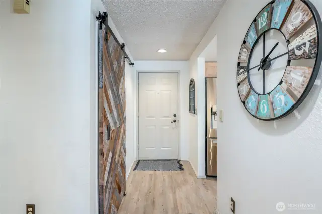 Entryway features a stylish sliding barn door over a closet adorned with shelves. Use it for storage or as a pantry!