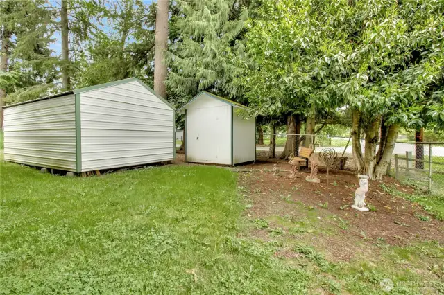 The backside of the metal carport and one of the sheds in the front yard. There's also a cute "parked out" area with a bench.