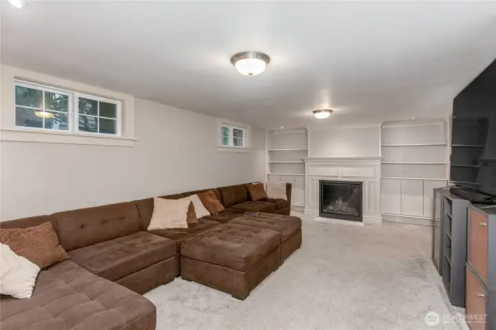 Fully finished rec room with gas fireplace and built-in bookshelves.