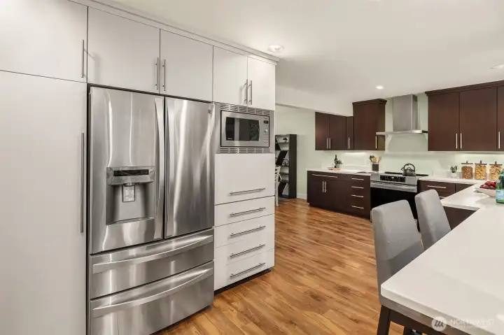 The cabinet to the left of refrigerator has pull out drawer with USB plug for charging convenience. There is a garage door appliance hideaway under the microwave to store your larger pots and appliances. Below the appliance hideaway, is a double drawer for tall cereal boxes, etc.