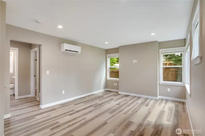 Step through the front door into a spacious living room filled with natural light, an efficient ductless heat pump for year-round comfort, and large windows fitted with fresh blinds.