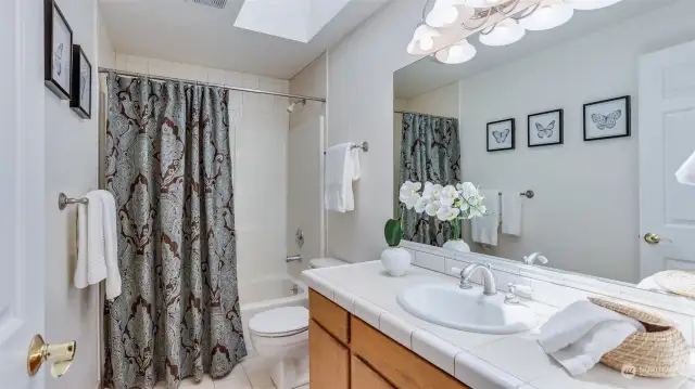 Full guest bath upstairs enjoys skylight.