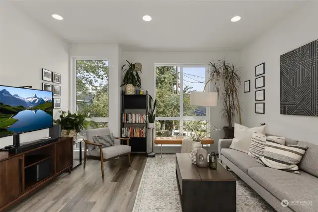 Thoughtful design elements, including stylish furniture, art, and large windows, create a warm and welcoming atmosphere in this bright, airy living room.