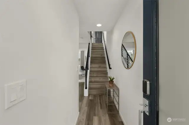 Step inside to a bright, inviting foyer with stylish wood flooring and a modern staircase leading to the upper levels.