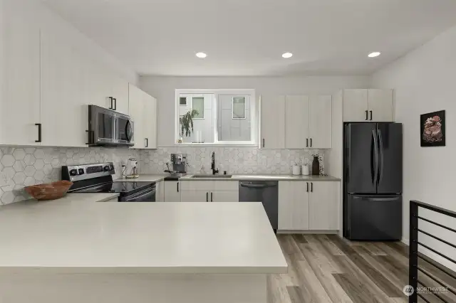 The kitchen's sleek black appliances contrast beautifully with the crisp cabinetry. It is a perfect blend of style and function for all your culinary needs.