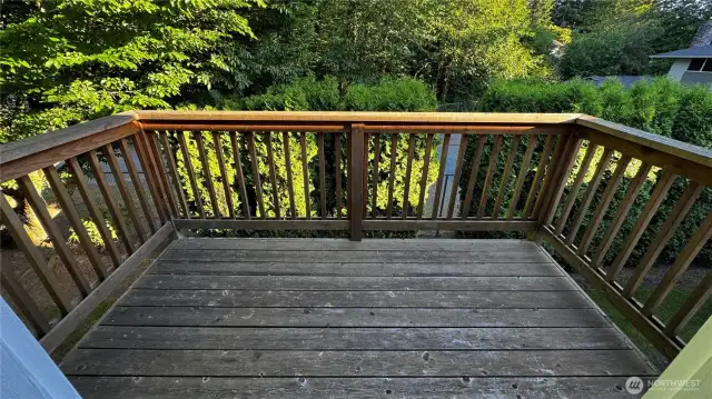 Quiet back porch space with access from the kitchen and tree-lined views.