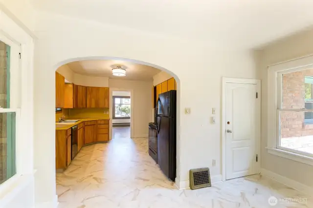 Beautiful arched entryway to kitchen. Easy care vinyl flooring in kitchen and dining areas. Door to basement is on the right.