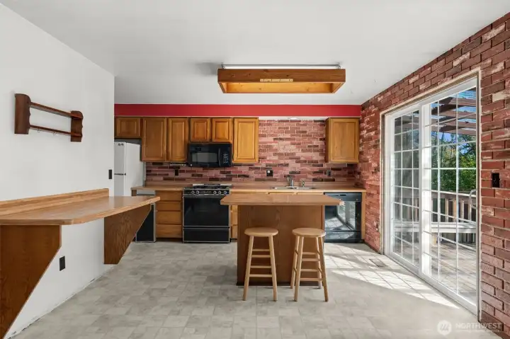 The kitchen showcases a central island with direct access to the covered deck, creating an ideal space for entertaining in any season.