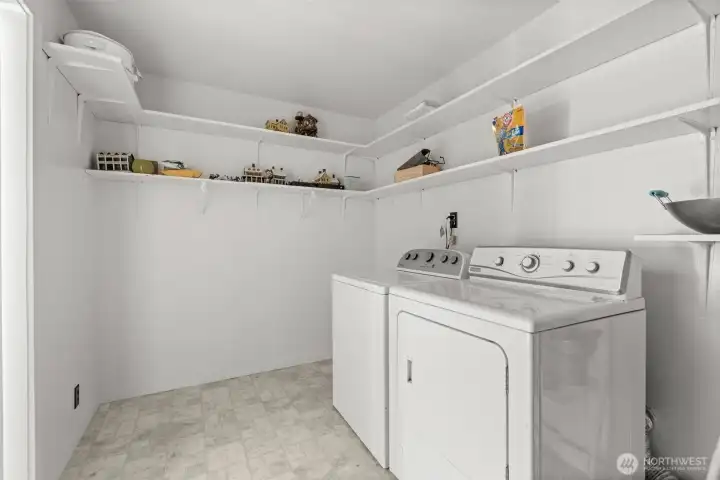 Function meets convenience with a large laundry room located off the dining area — the perfect drop zone when coming in from the garage, complete with generous storage and built-in shelving.