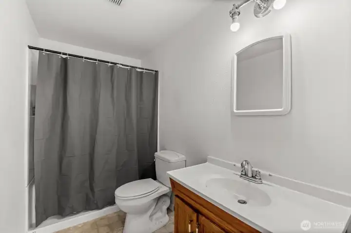 The main-floor bathroom features a fiberglass standing shower with a low-curb entrance, designed for easy accessibility.