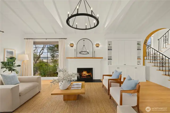 The new gas fireplace is flanked by an original leaded glass window with views of Lake Washington and a custom-made cabinet with plenty of storage and a hidden TV that swivels for easy viewing throughout the room.