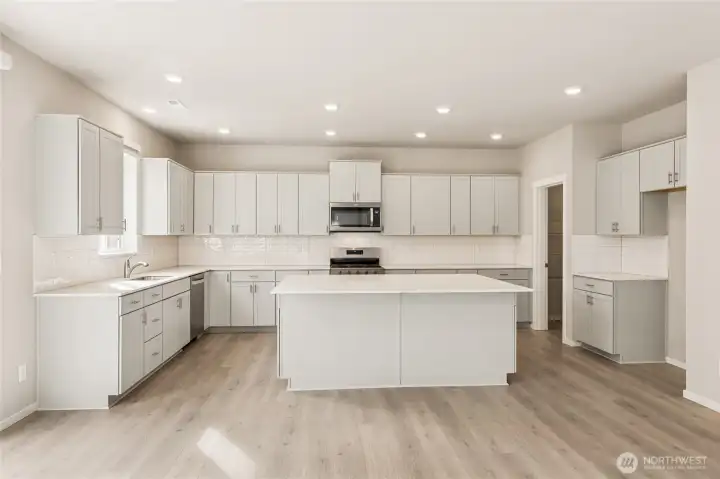Chef's kitchen with shaker-style cabinetry, white quartz countertops, a large center island with bar seating, stainless steel appliances. Photos are representative only and may display different color package and/or upgrades.