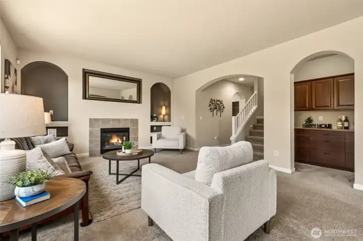 Warm living room featuring a gas fireplace, charming arches, and comfortable, light-filled space. -- The recessed nook is perfect for a planning area, coffee or wine bar! (Insert a wine cooler below the counter?!?)