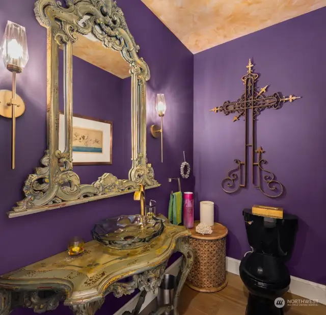 The powder room features a striking glass vessel sink atop a beautifully hand-painted vanity, adding a touch of sophistication.