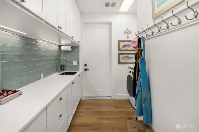 Even the utility room impresses with its generous scale, offering an abundance of custom cabinetry complemented by charming sea star subway tile.