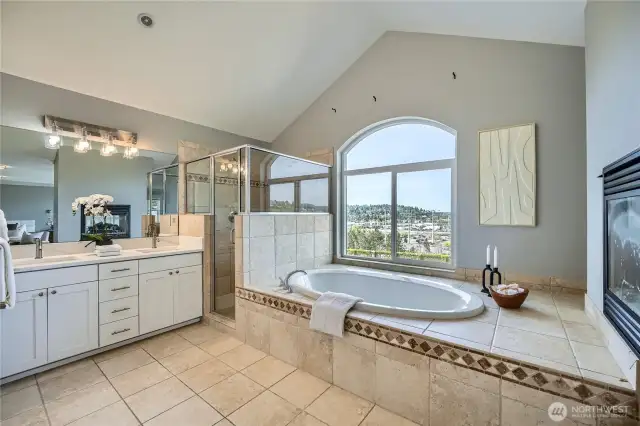 Luxurious primary bathroom featuring dual sinks, a large soaking tub with stunning city views, and a spacious walk-in closet for ample storage and convenience. Freshly updated with new quartz countertops for a modern, elegant finish.