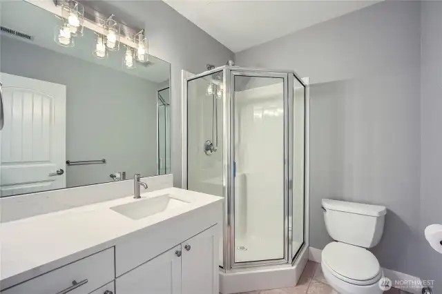 Updated 3/4 bathroom on the lower level featuring a sleek new quartz countertop, blending modern style with practical comfort.