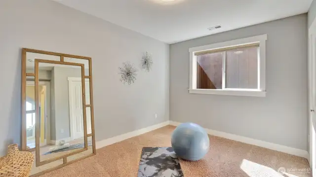 This versatile space offers endless possibilities, whether used as a bedroom, home office, flex room, or personal exercise studio. Bathed in natural light from the large window, the room features soft carpeting and a soothing color palette that promotes comfort and focus. A large decorative mirror and modern wall accents add style, while the open layout provides ample room for yoga, stretching, or strength training. Whether you're looking for a peaceful retreat or a productive workout space, this flexible room adapts seamlessly to fit your lifestyle needs.