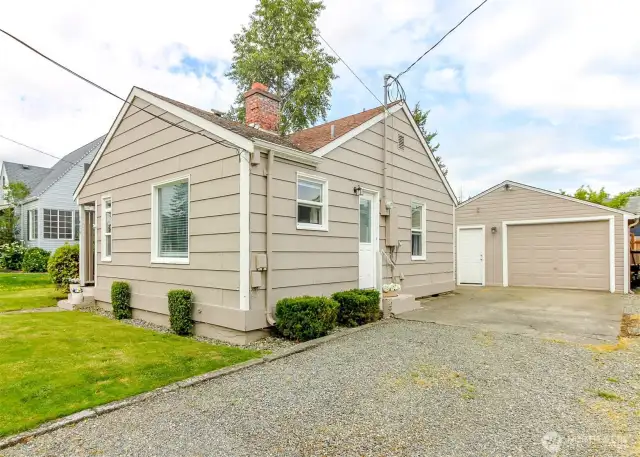 Long driveway featuring plenty of parking spaces with additional covered parking in detached garage