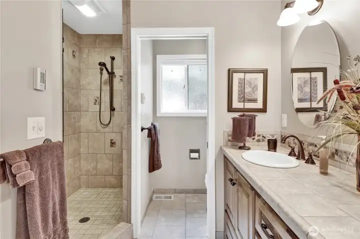 The primary bathroom features a large walk-in shower, radiant heated tile floors, and a double-sink vanity for both style and convenience.
