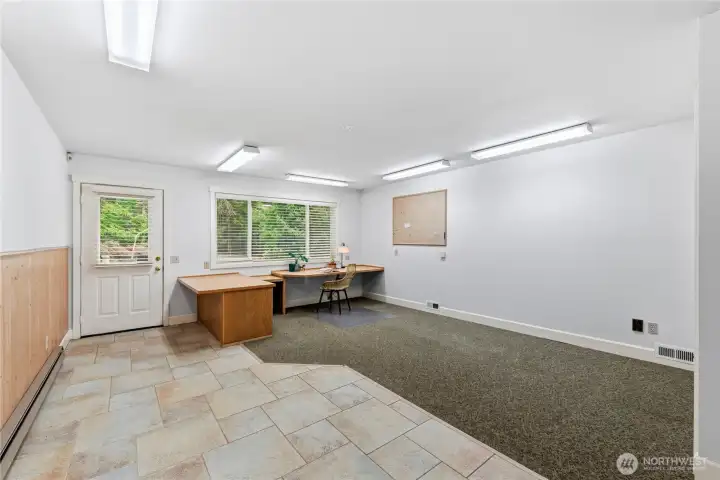 Spacious attached office featuring a custom built-in desk, large window for natural light, and a separate private entrance, making it ideal for working from home, a creative studio, home gym, or guest flex space.