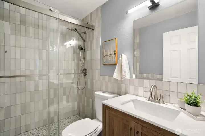 The stylish primary bath has modern tile and lighting.