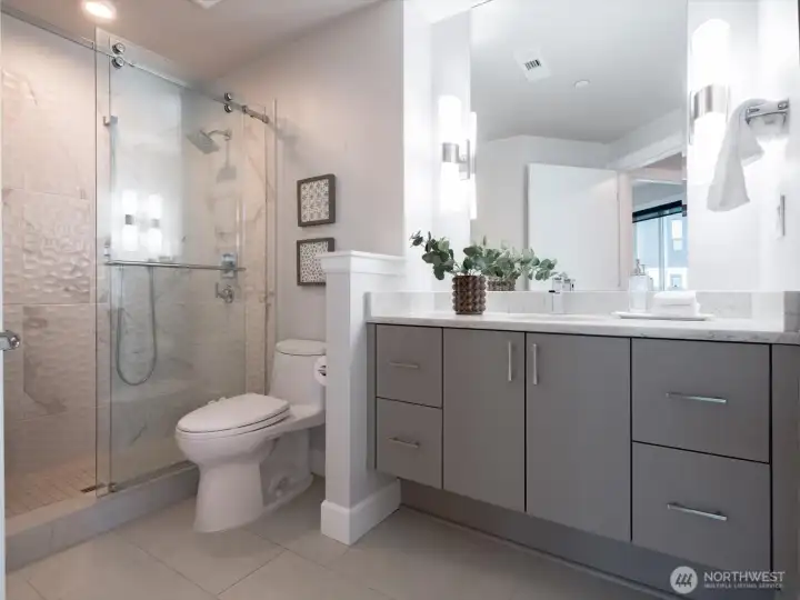 Sleek guest bath featuring glass enclosed shower, quartz, and designer tile finishes. All cabinetry features the soft-close touch. Sleek guest bath featuring glass enclosed shower, quartz, and designer tile finishes. All cabinetry features the soft-close touch.