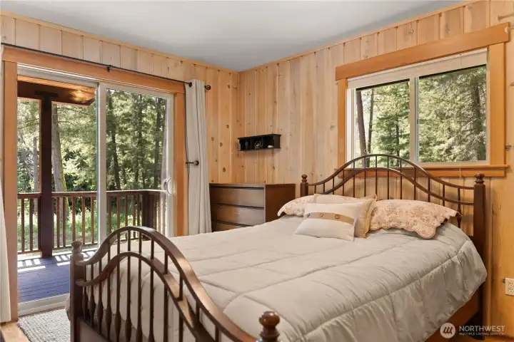 Main-level bedroom with private deck access and lovely river views. Main-level bedroom with private deck access and lovely river views.