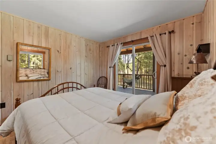 Wake up to filtered sunlight and river views. This cozy bedroom features pine-paneled walls and a sliding glass door that opens directly onto the deck—perfect for morning coffee or a quiet sunset unwind. Wake up to filtered sunlight and river views. This cozy bedroom features pine-paneled walls and a sliding glass door that opens directly onto the deck—perfect for morning coffee or a quiet sunset unwind.