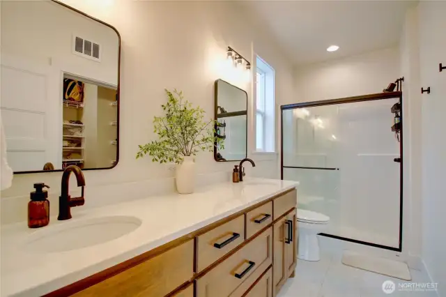 Primary ensuite with walk-in shower, dual vanities, and walk-in closet