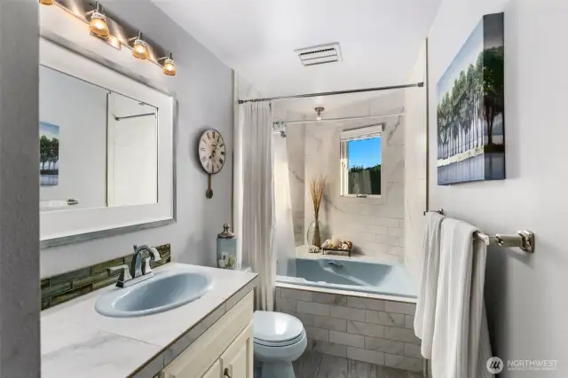 Full bathroom w/garden tub surrounded by floor to ceiling tile.
