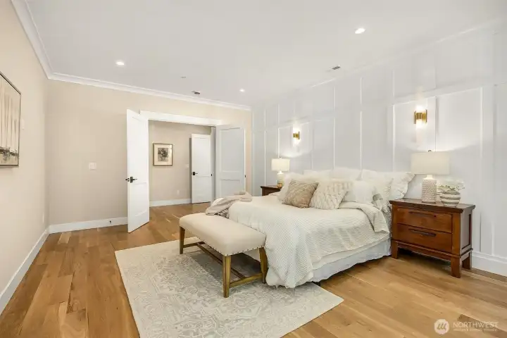 This angle of the primary suite shows off the beautiful wainscoting on the walls and wall sconces for different lighting options.
