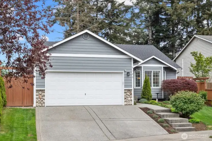 Welcoming front elevation w/ mature landscaping, new roof, & a thoughtfully maintained exterior.