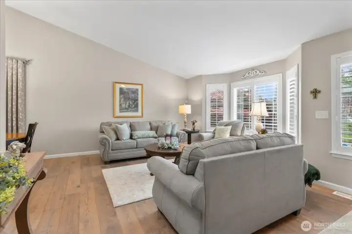 Light-filled living room featuring plantation shutters, engineered hardwood flooring, & an inviting open layout.