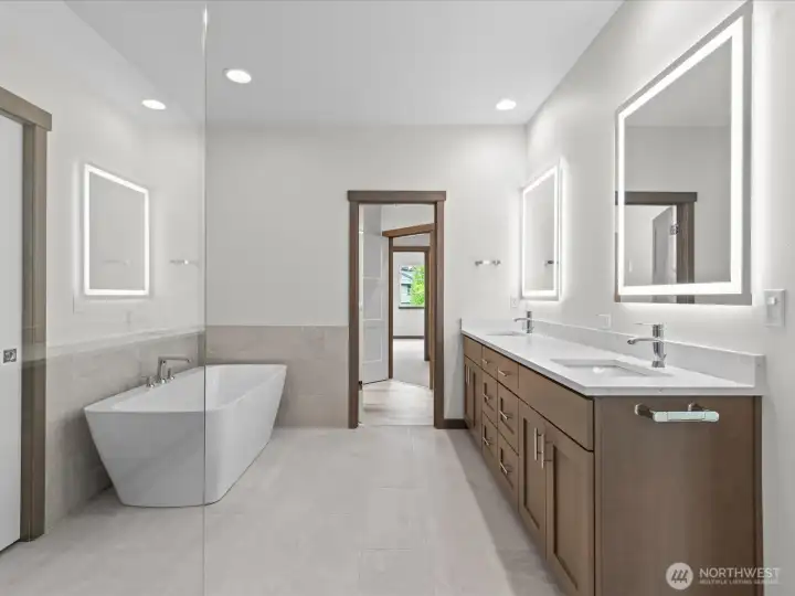 Sophisticated primary bath featuring a premium double vanity, integrated LED mirror lighting, a freestanding standalone tub, and an elegant glass-enclosed shower.
