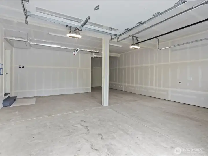 Spacious, extra-deep 2-car garage equipped with a dedicated EV charger. Offers plenty of room for oversized vehicles, a home workshop, or premium additional storage.