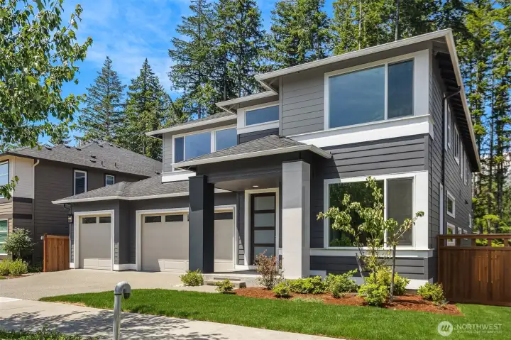 Modern MainVue  "Lotus" exterior with bold Northwest architecture, 3-car garage, and a mature greenbelt backdrop.