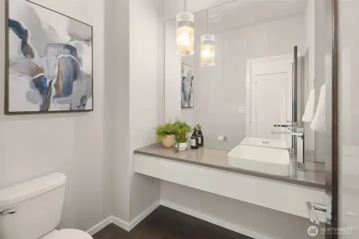Stylish powder bath with floating vanity, vessel sink, contemporary fixtures, and elevated designer lighting.
