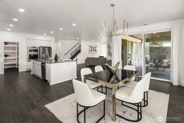 Dining area framed by oversized windows and sliding doors, connecting directly to the covered Signature Outdoor Room.