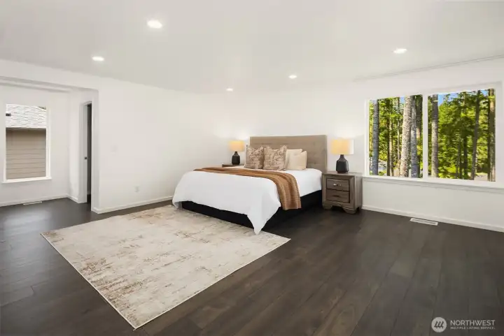 Oversized primary retreat with generous open space, clean modern finishes, and a peaceful wall of windows overlooking the trees.