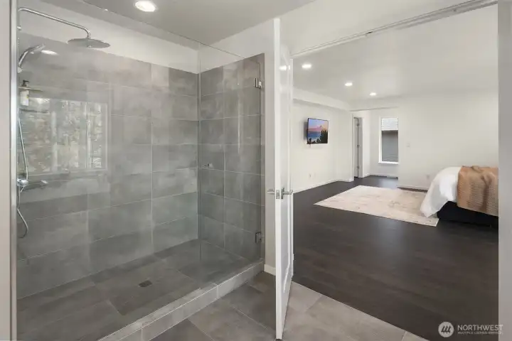 Oversized walk-in shower with floor-to-ceiling tile, frameless glass enclosure, and a rainfall showerhead for a polished, spa-like experience