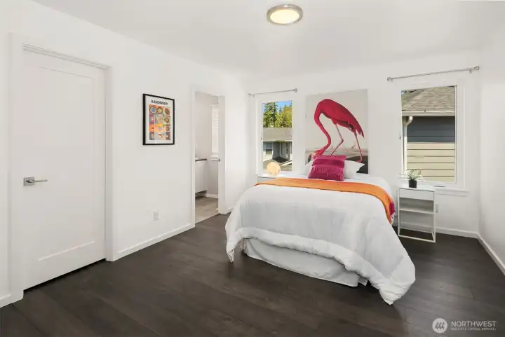 Generous bedroom suite with private bath access, modern flooring, and a bright, fresh design.
