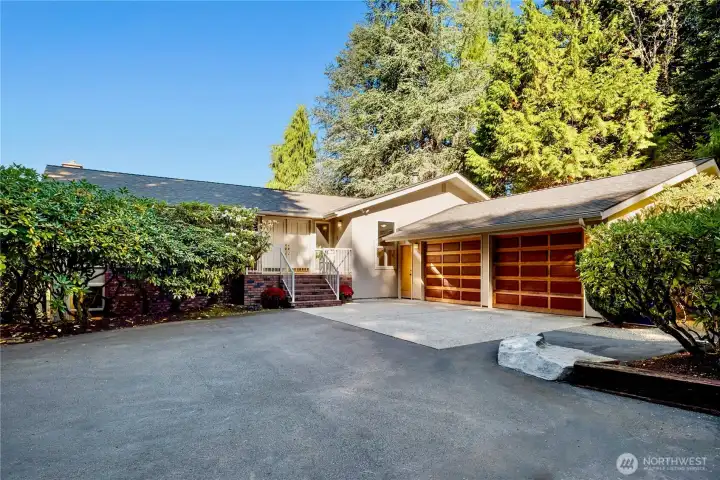 The home’s welcoming entry features double doors and a spacious 2-car garage framed by mature landscaping.