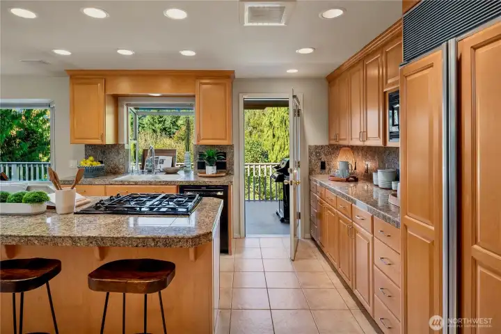 A wall of windows invites the outdoors in, filling the kitchen with natural light while offering easy access to the expansive entertaining deck.