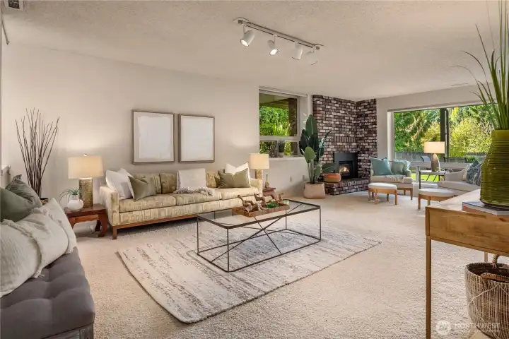 Spacious lower level family room framed by a classic brick fireplace and large windows showcasing the private, tree-lined backyard.