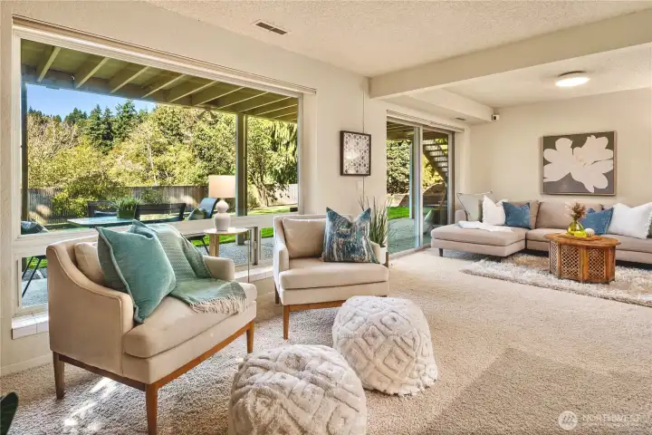 Expansive family room with a wall of windows overlooking the lush yard, creating a serene backdrop for everyday living and a great getaway spot for movie night, games and more.