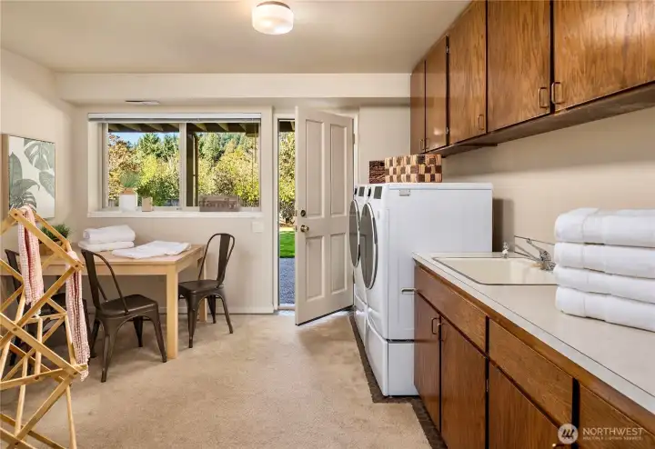 Thoughtfully designed laundry and craft space with built-in cabinetry, folding area, utility sink and direct access to the outdoors.