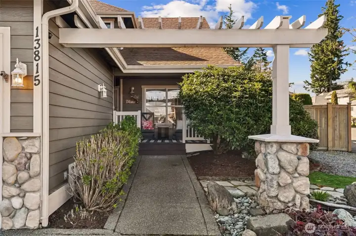 Inviting front entry with a charming pergola-covered walkway leading to a warm and welcoming porch.