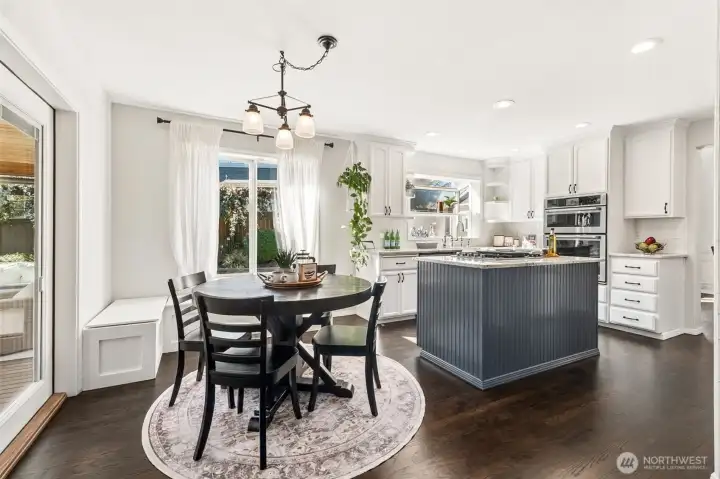 Stunning kitchen featuring a statement island, crisp white cabinetry, and a bright dining nook framed by large windows and natural light.