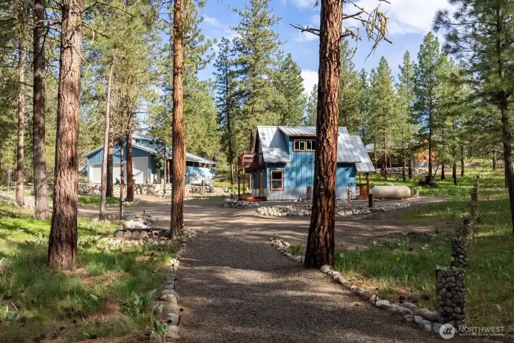 Well maintained 1 Acre Lot and landscape is meticulously cared for. 942 SF  tiny home and additional outbuilding of 200 sf for small office, Artist studio or guest space as you desire. Solid Garage and shop is 1440 sf. Exceptional quality throughout.  Trails to each building. Private well. Delicious water found here!